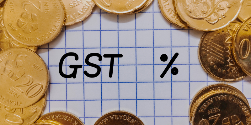 "Singapore GST is illustrated with gold coin on the grid paper written GST. "